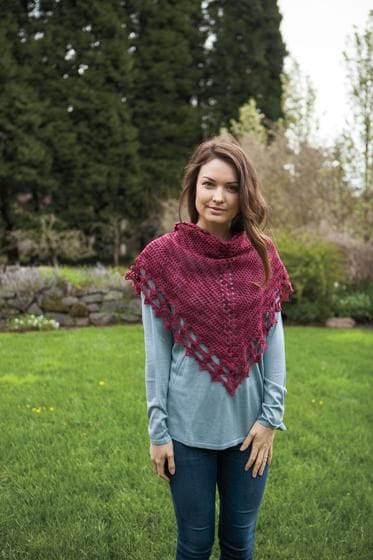 A model wears a triangular red crochet shawl around her neck.