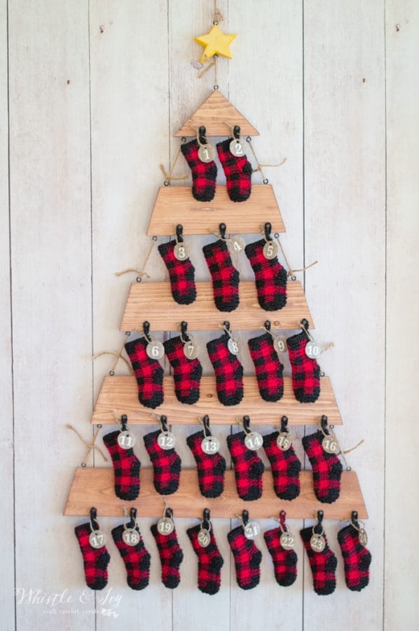 Crocheted plaid mini stockings on an advent calendar shaped like a Christmas tree.