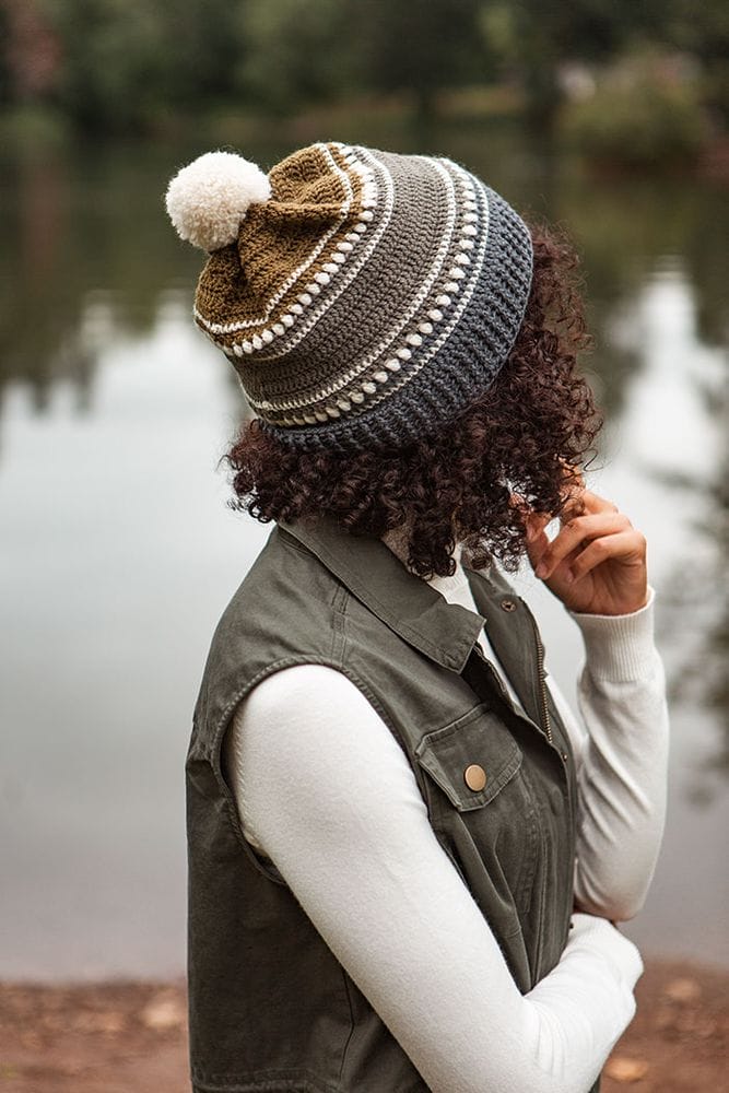 A model wears a crocheted hat with a white pom-pom