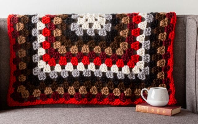 A crocheted granny square throw blanket
