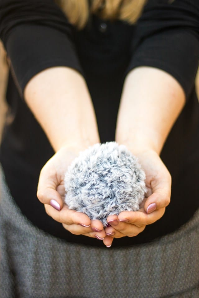 A woman holds a faux fur pom pom in her hand