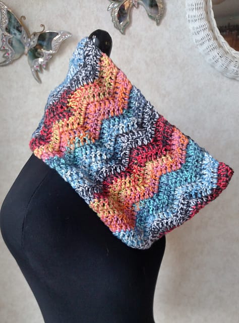 A picture of a colorful zig-zag scarf cowl on a mannequin. The Felici on the Double Cowl by Sati Glenn.