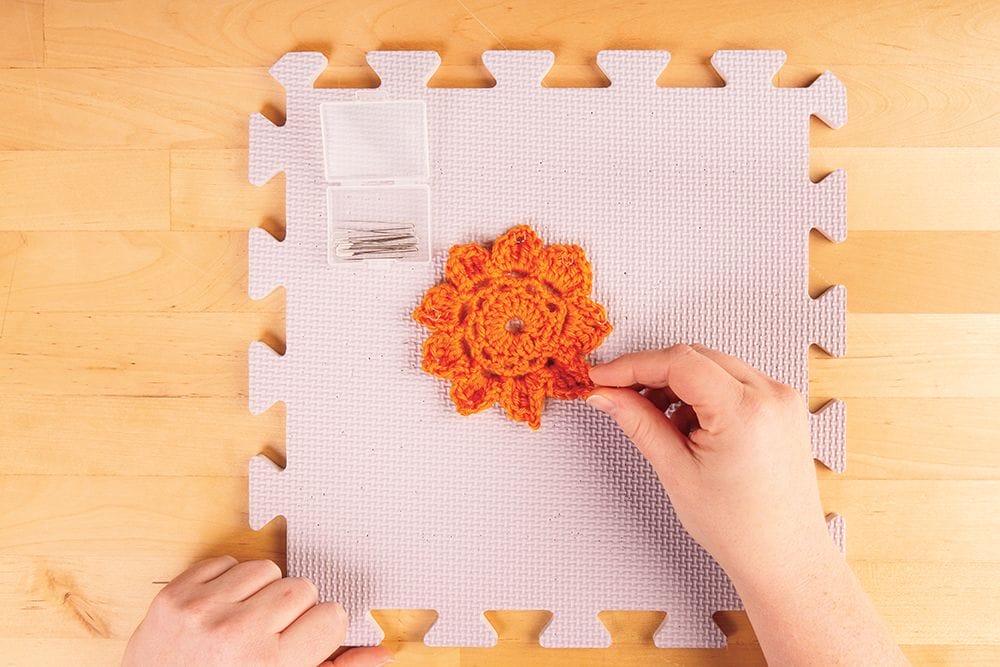 Blocking crocheted flowers on a blocking mat, with T-pins