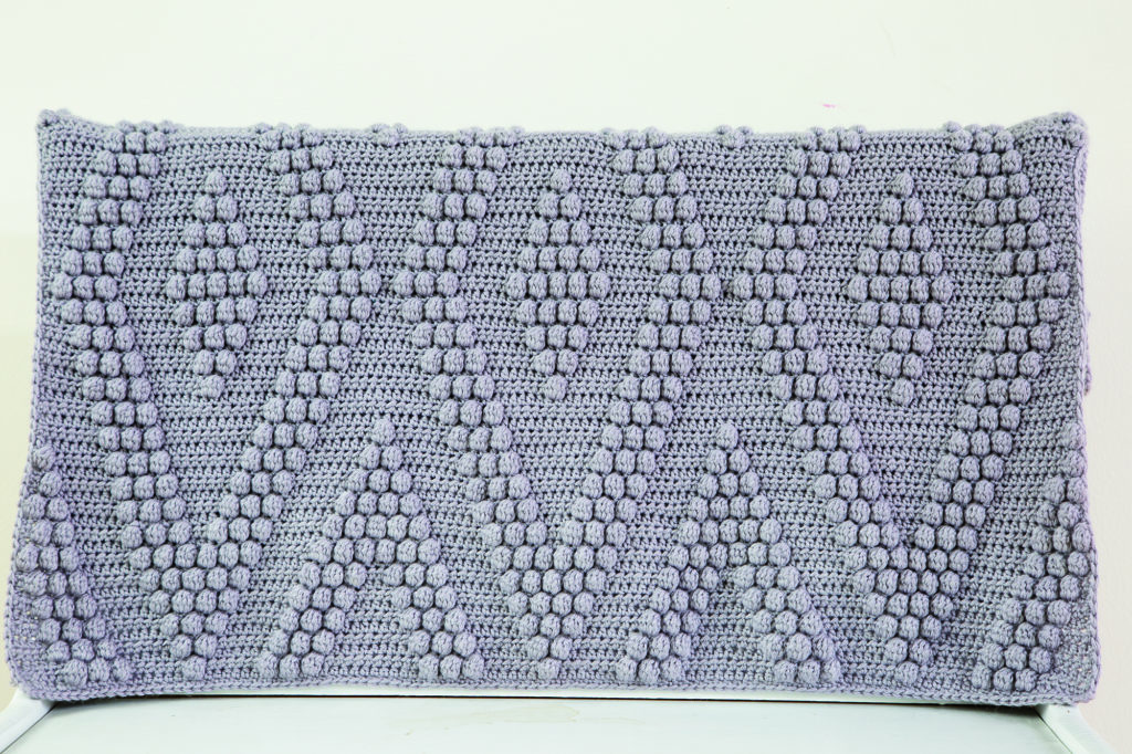 The Bobble Diamonds Throw: A gray crocheted blanket with a geometric diamond pattern made in bobble stitches