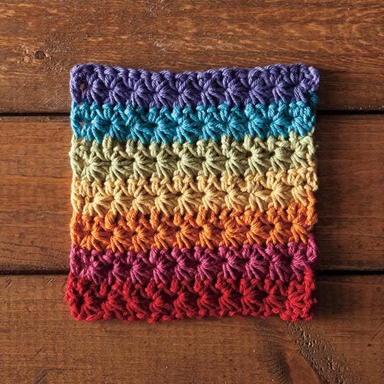 A dishcloth crocheted in an interesting stitch, made in bands of rainbow color
