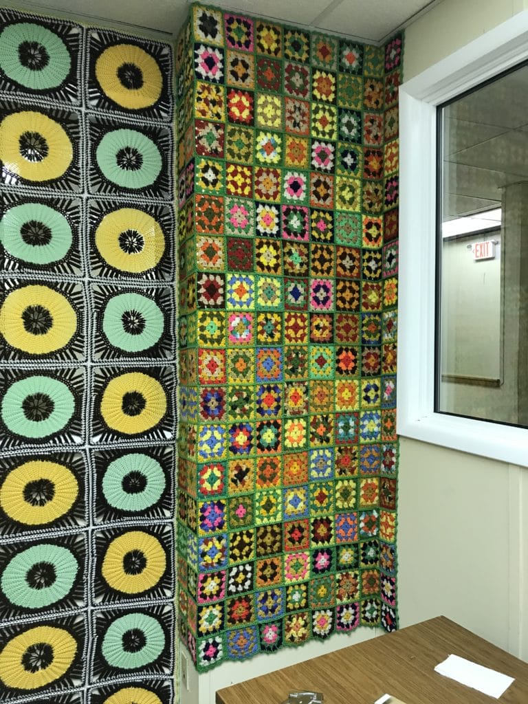 An office wall is covered with vintage afghans