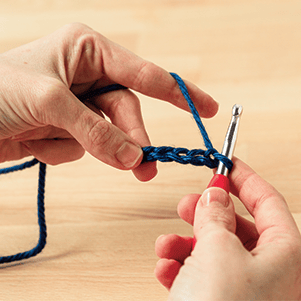 two hands displaying 5 chains and a crochet hook.