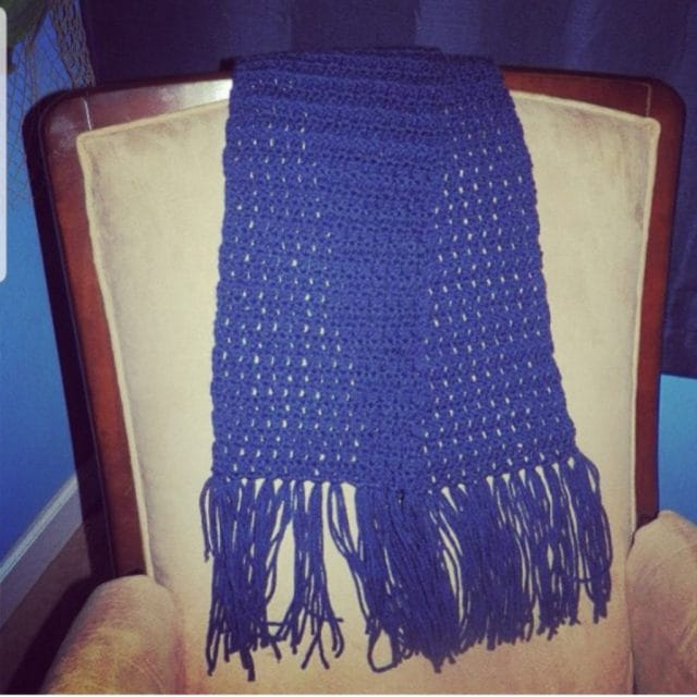 Michelle's first crochet project: A navy blue scarf (with fringe) draped over a chair