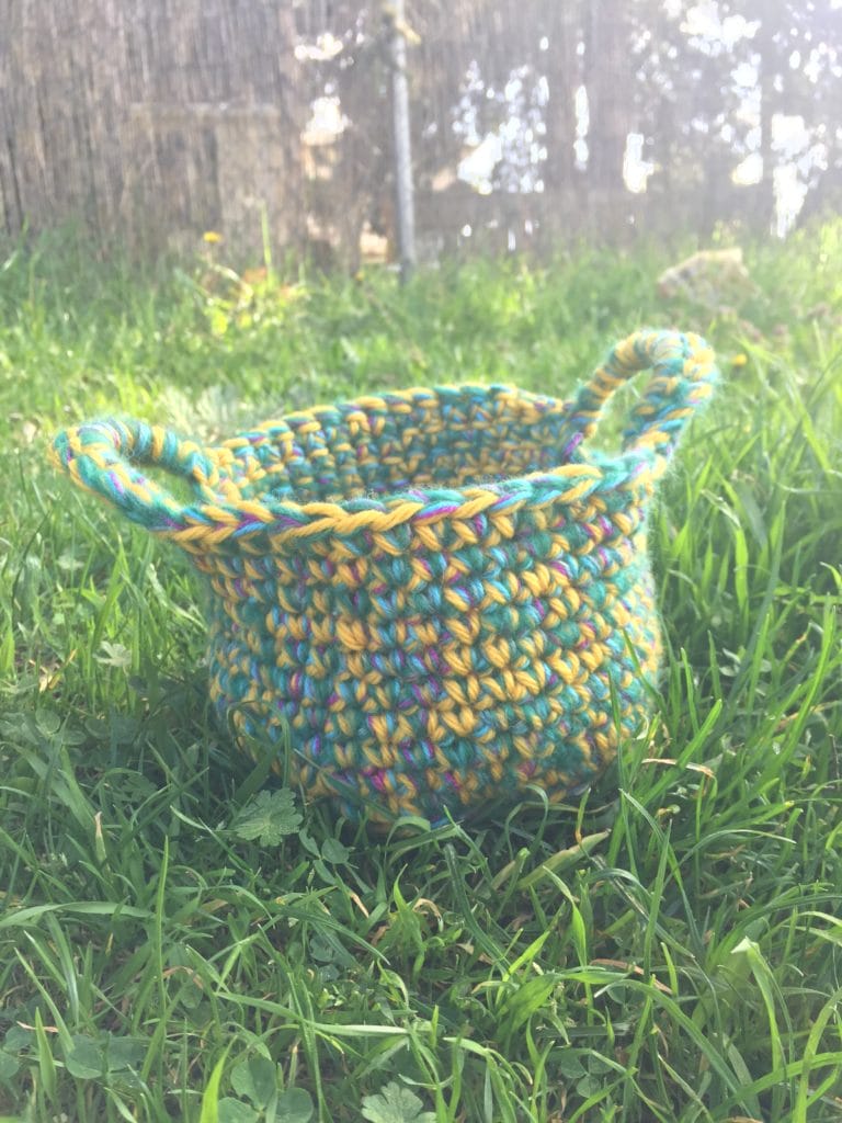 A crocheted easter basket sitting in the grass