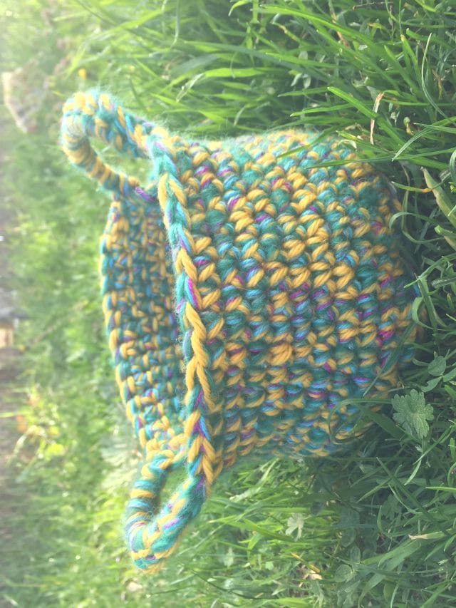 A crocheted easter basket sitting in the grass