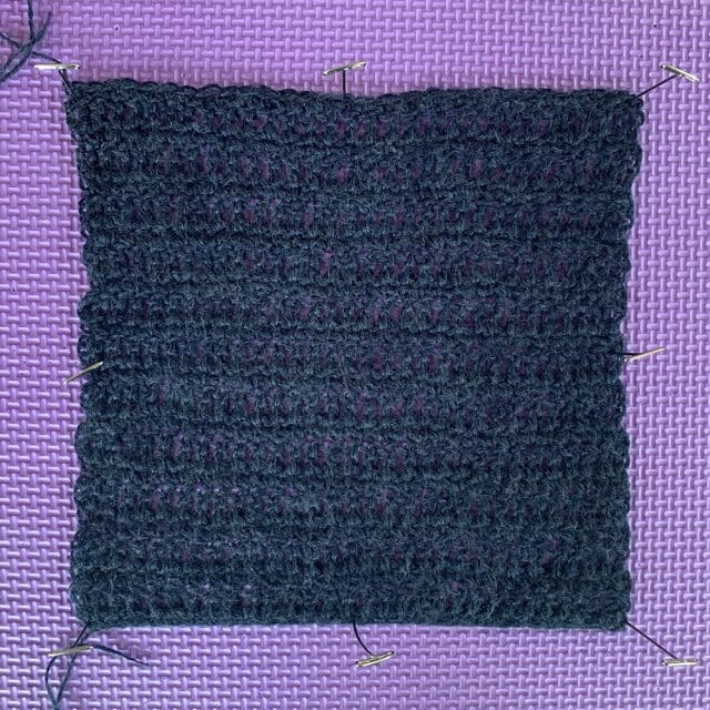 A crochet swatch blocking on a mat. Capretta Superwash in Meridian Heather