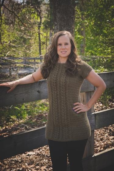 Michelle models her Aspen Tunic, a hip-length crocheted sweater made in brown, with cables running up the front.