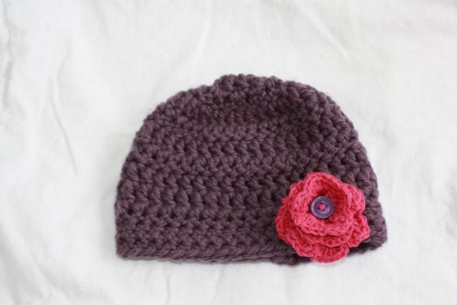 Michelle's first crochet project: a purple hat with a bright pink flower on it.