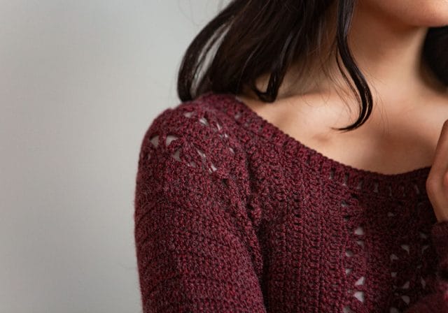 A detail of the Light Touch Pullover: the shoulder of the dark red crocheted sweater