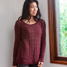 a model wears a hand-crocheted sweater in dark red
