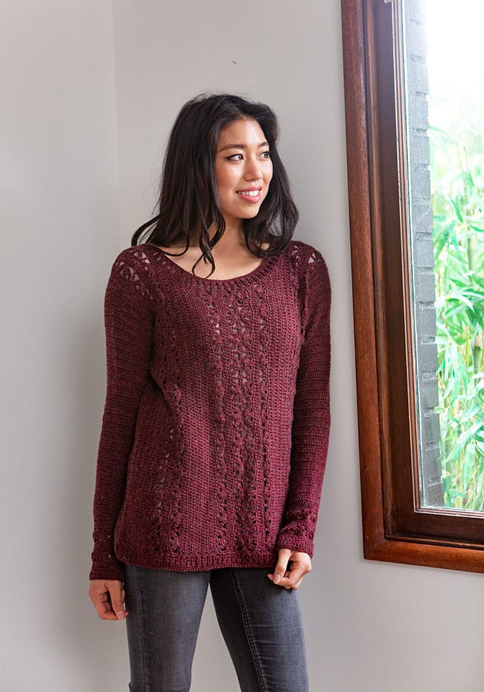 A woman wears a lovely dark red crocheted sweater
