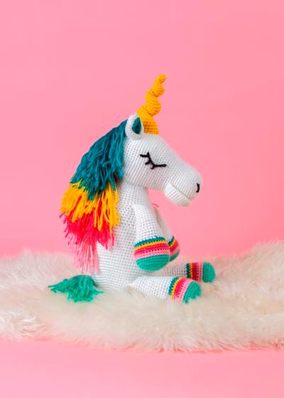 A crocheted unicorn toy with a rainbow-colored mane