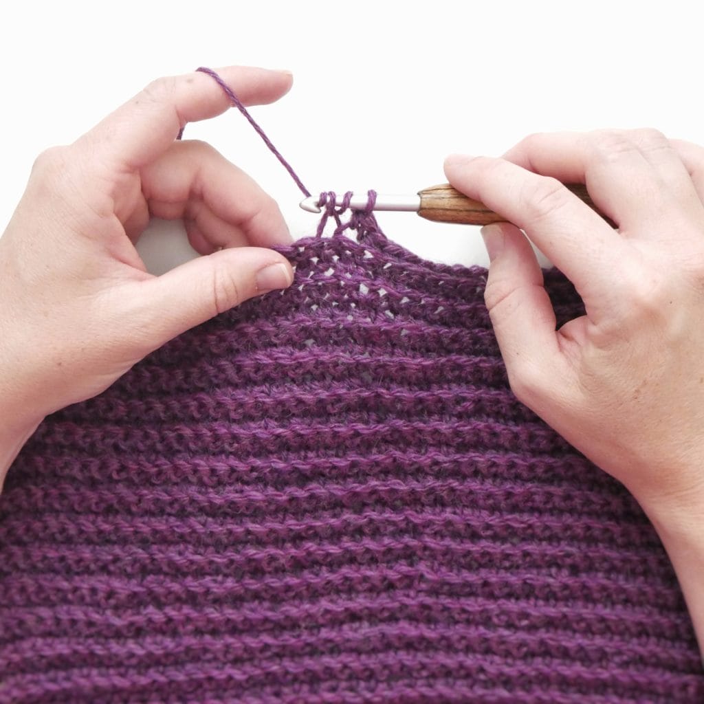 Single crochet back loop only (BLO) crochet swatch. Hands crocheting a purple crochet swatch with a wooden-handled crochet hook