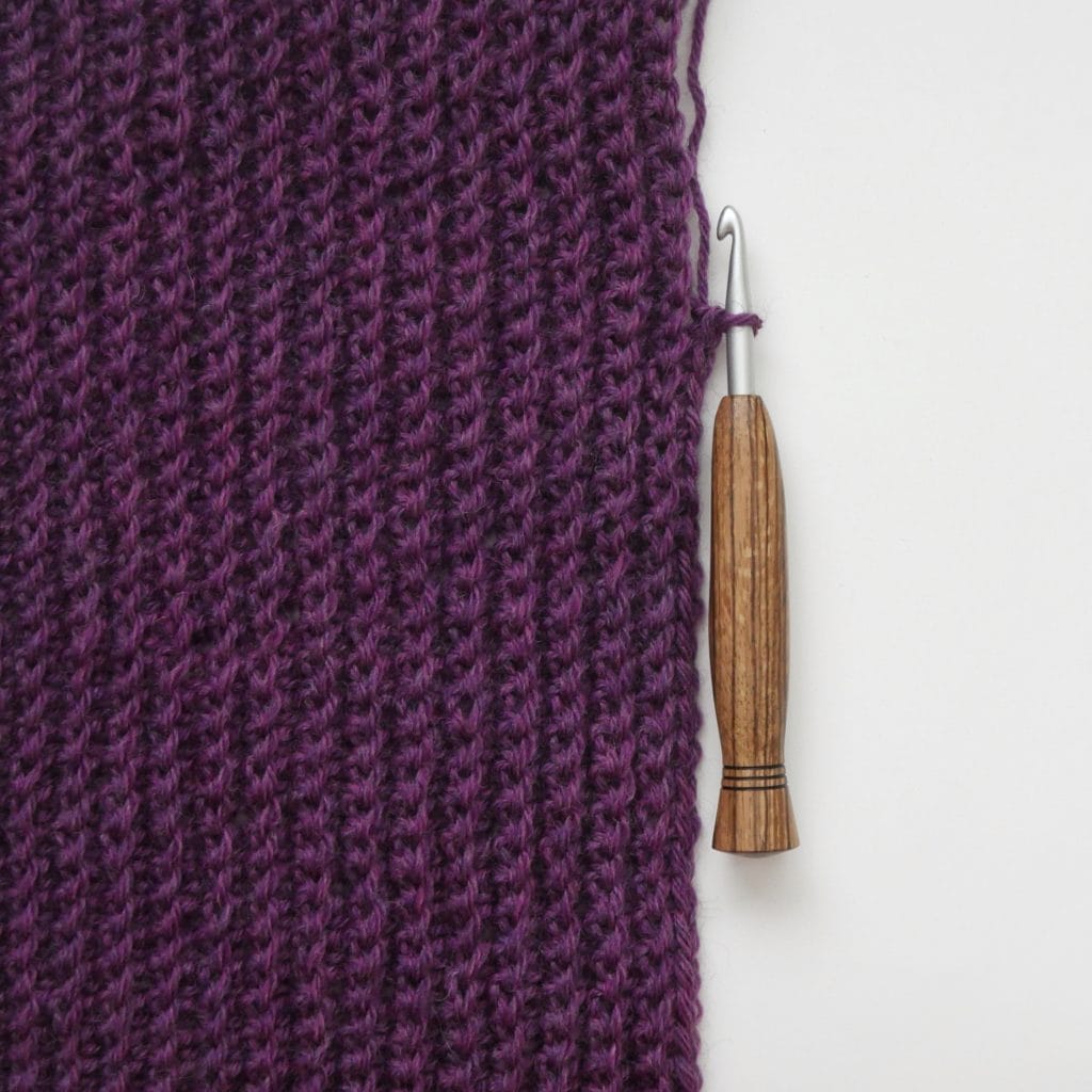 Single crochet back loop only (BLO) crochet swatch. a purple crochet swatch with a wooden-handled crochet hook