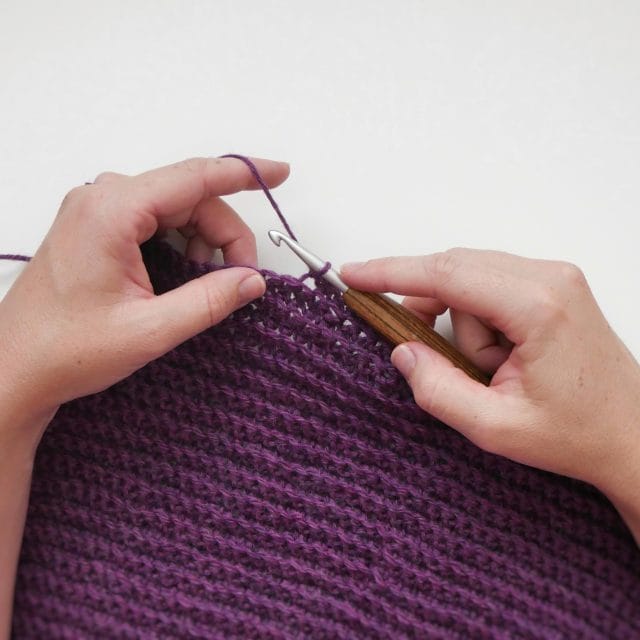 Single crochet back loop only (BLO) crochet swatch. Hands crocheting a purple crochet swatch with a wooden-handled crochet hook