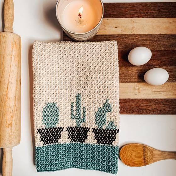 a crocheted dishtowel with a cross-stitched pattern of 3 cactuses