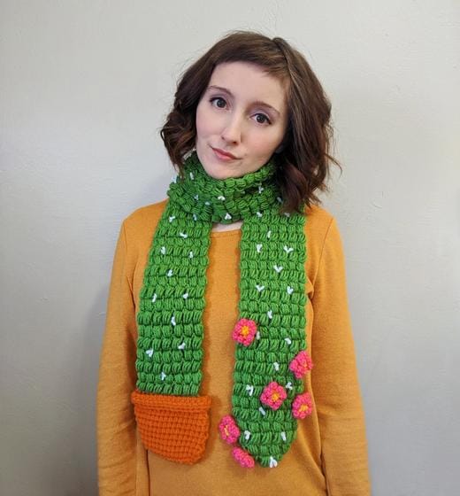 a woman wears a crocheted cactus scarf