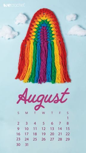 On a sky-blue background, a crocheted rainbow wall hanging, reminiscent of macrame, in rainbow colored puff stitches: red, orange, yellow, green, blue, purple. In the background, clouds made of cotton batting. At the bottom, an August 2020 calendar in purple.