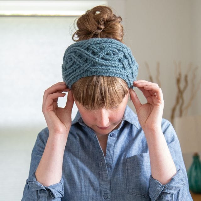 a model tips her head forward to show off a cabled headband