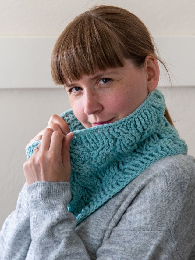 a model wears a crocheted cable cowl