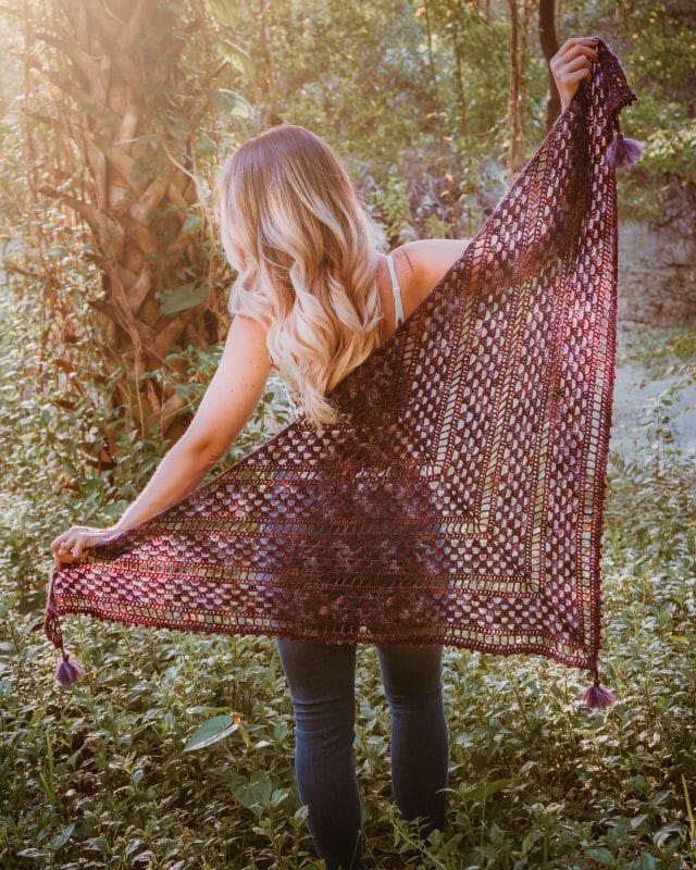 Picot Crochet Shawl pattern by Briana K Designs. A model holds the plum-colored crocheted shawl out behind her to show its wingspan.