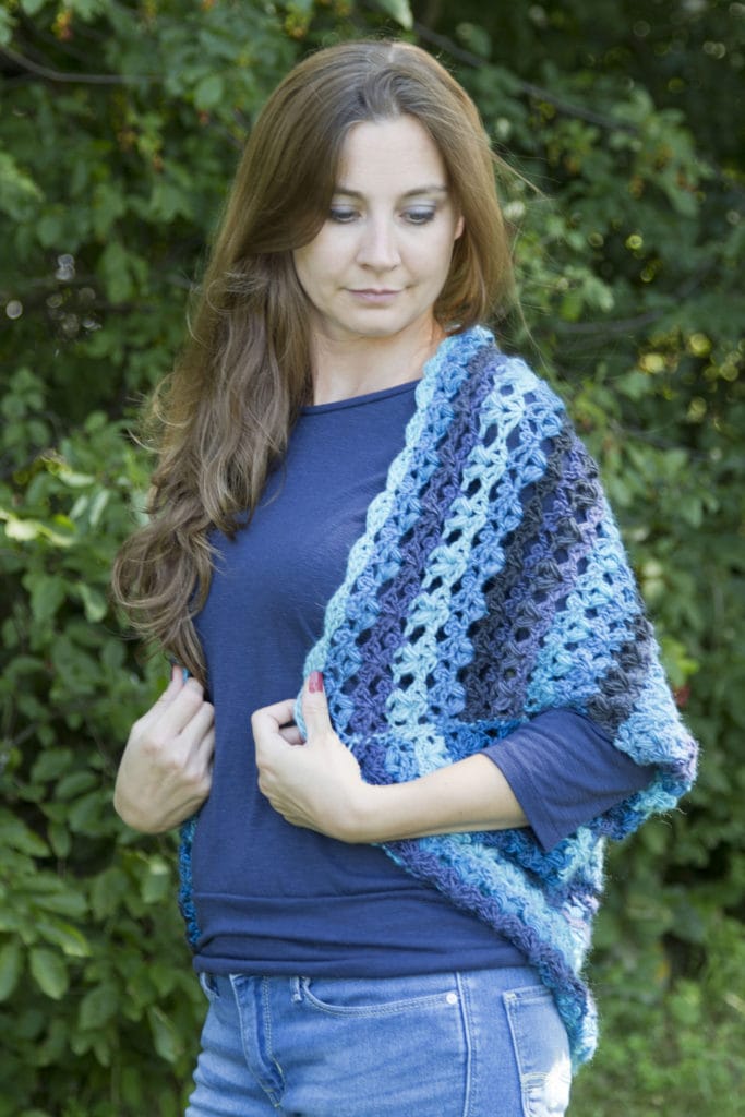 KoKo Cocoon Cardigan by Crystalized Designs. A model wears a gradient blue crocheted shrug.