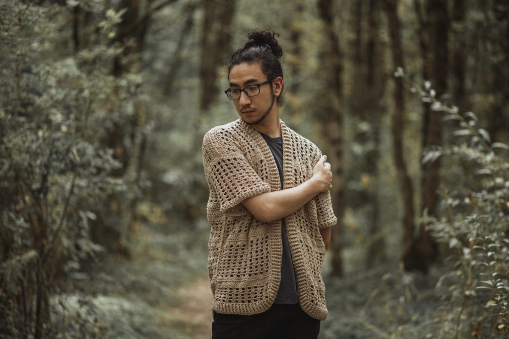 Regan wearing a crocheted sweater of his own design, demonstrating slow fashion.