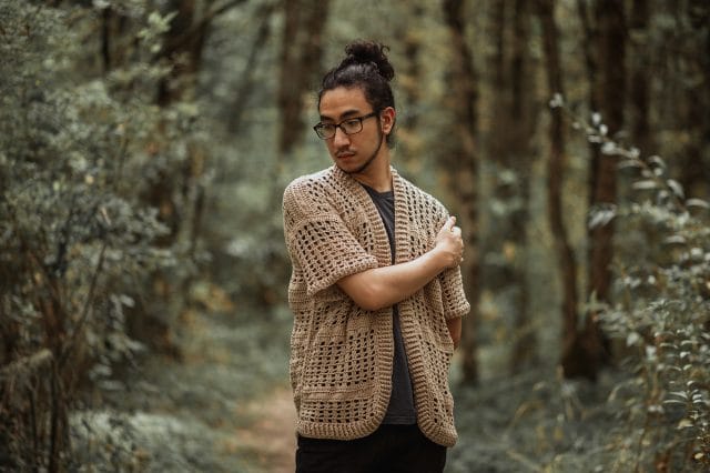 Regan wearing a crocheted sweater of his own design, demonstrating slow fashion.