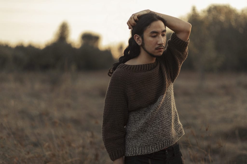 Regan wearing a handmade sweater. Slow fashion is participating in creating your own wardrobe, whether through sewing, crocheting, knitting, or other methods.