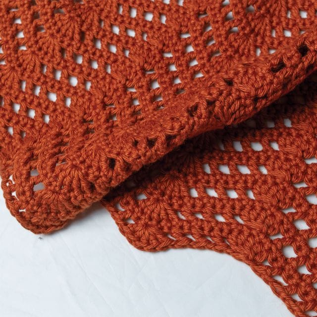 A close up of the Bambino Ripple Blanket, a copper-colored crochet ripple blanket, part of the free crochet patterns of Crochet.com's 12 Weeks of Gifting.