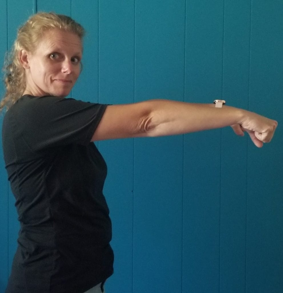 Another of our crochet stretches: An image of a woman stretching her arm out from her chest with her hands in fists facing downward.