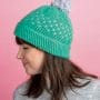 A model wears a crocheted hat with a pom-pom