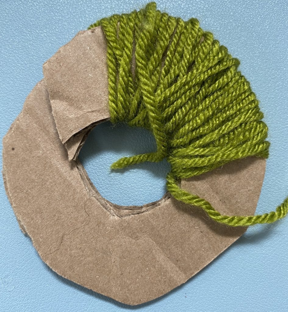 10 Thrifty Crochet Tips from the WeCrochet Blog at crochet.com. This photo shows: a cardboard circle being used as a pom-pom maker.