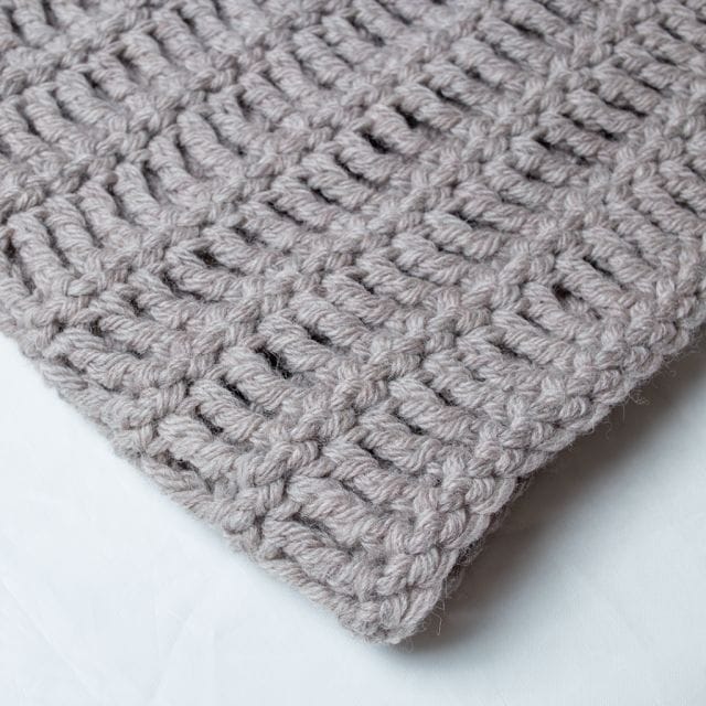 An oversized gray crocheted scarf. The Vanilla Latte Super Scarf, part of the 12 Weeks of Gifting, free crochet patterns from crochet.com