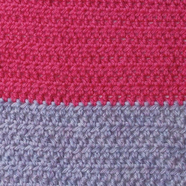 Crochet.com gives away a free crochet pattern every week during the 12 weeks of gifting! This week's pattern is the Bright Gifts Wrap. Image shows: a closeup of the crocheted texture of the wrap, in two swaths of magenta next to lavender yarn.