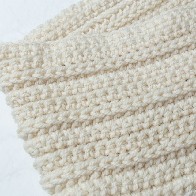Crochet.com gives away a free crochet pattern every week during the 12 weeks of gifting! This week's pattern is the Cozy Infinity Scarf. Image shows: a closeup of the crocheted texture of the Cozy Infinity Scarf, in cream-colored yarn.
