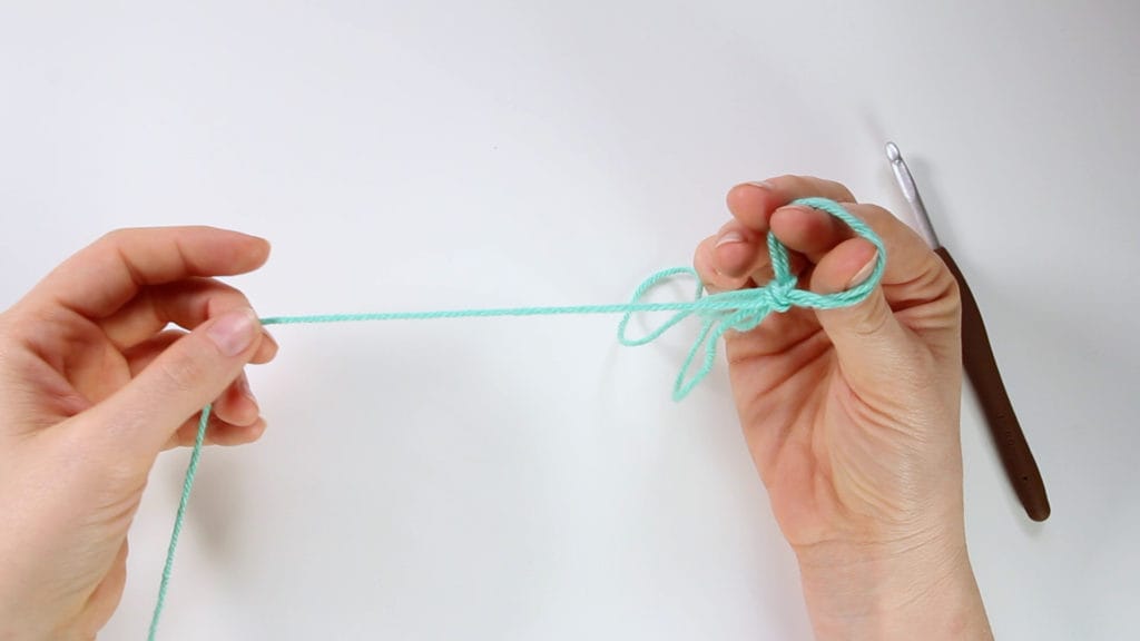 Pick up the single strand of yarn coming from cake or skein, and pull it through loop.