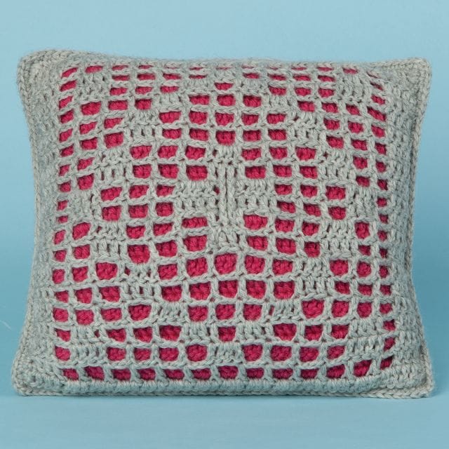 Warm Lights Pillow, a filet crochet design with a diamond pattern in sage green overlaid over a solid red background, a free crochet pattern from crochet.com