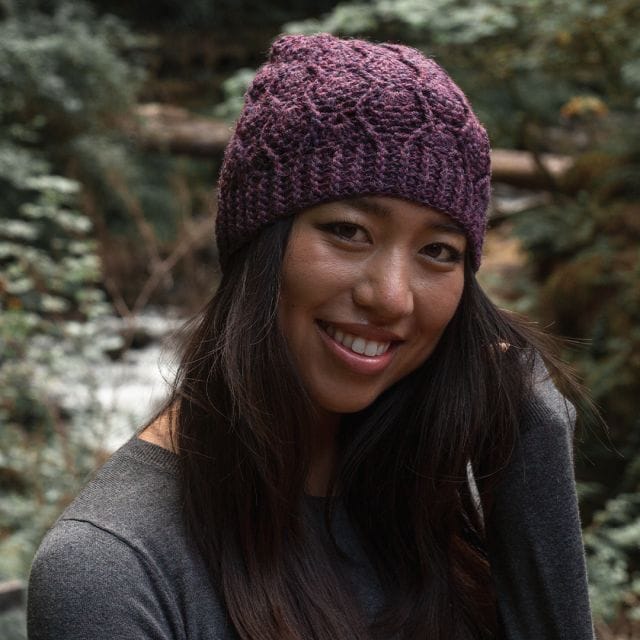 A model wears a crocheted hat: the Pineapple Beanie. A free pattern from crochet.com.