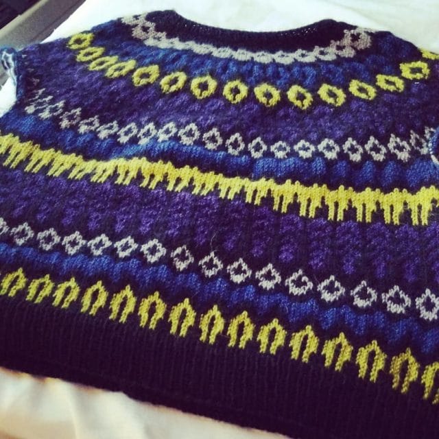 A knitted sweater by Elise, made in purple, blue, and chartreuse