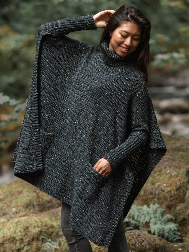 A model wears an oversized gray tweed crocheted poncho, the perfect winter crochet pattern.