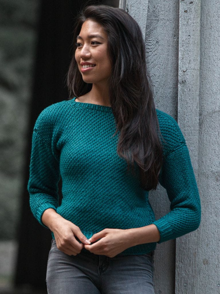 A model wears a teal crocheted sweater