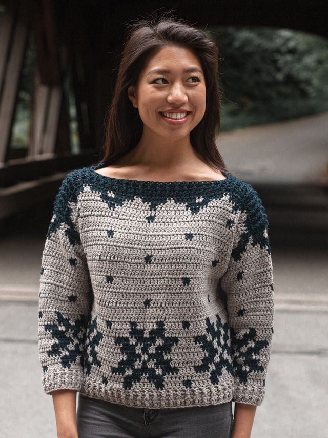A model wears a crocheted sweater with a snowflake motif.