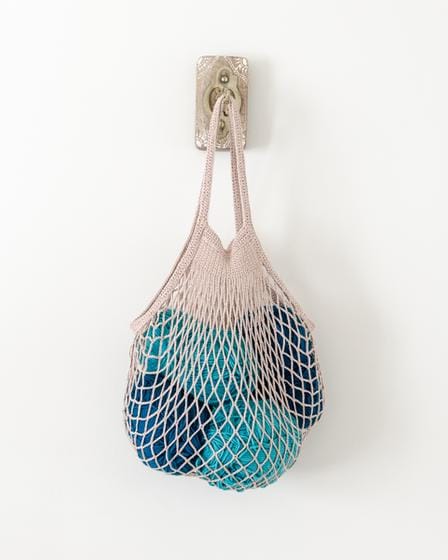 Crochet market bag is a mesh-like bag filled with yarn balls