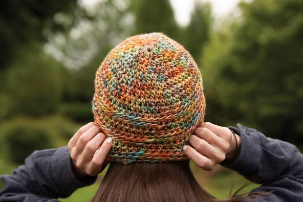 Leyla's Hat shown from the back: a crocheted hat made in multicolored orange-toned yarn